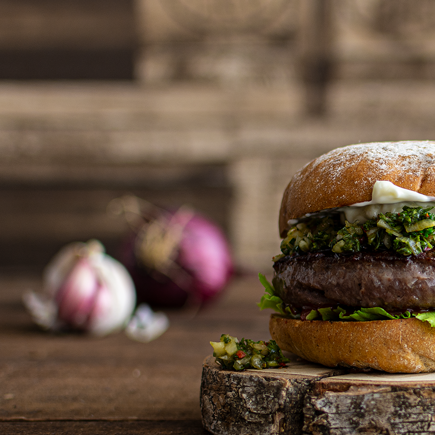 börger-online-kaufen, Burger Zubereitung, Wagyu Burger Patty angebraten mit Zwiebeln, Wagyu Burger Set kaufen, Burger Set mit Wagyu-Patties, Burger Set bestellen, ganzer Burger auf Holzbrett